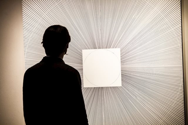 A man is silhouetted against a large black and white painting